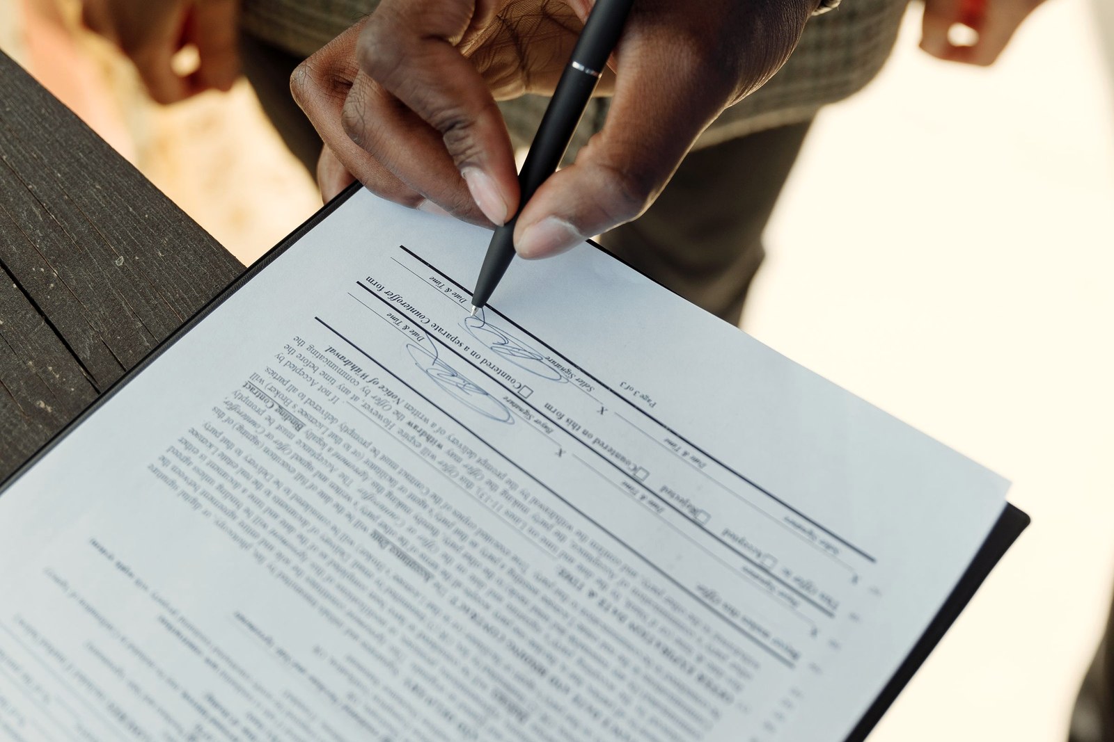 Pessoa assinando um contrato com caneta, momento em que o fiador assume a responsabilidade pela locação