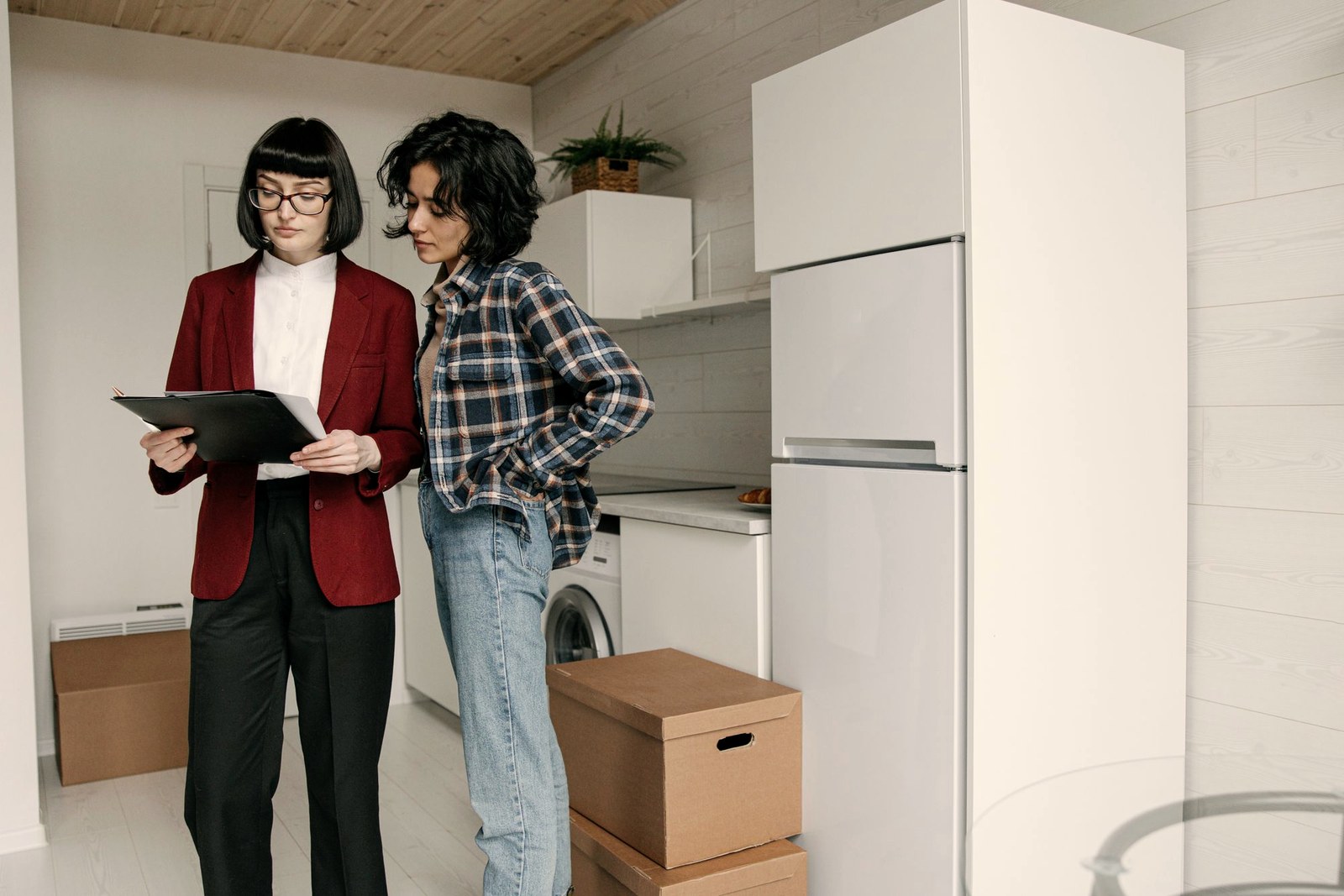 Pessoas conferindo documentos em um apartamento com caixas de mudança