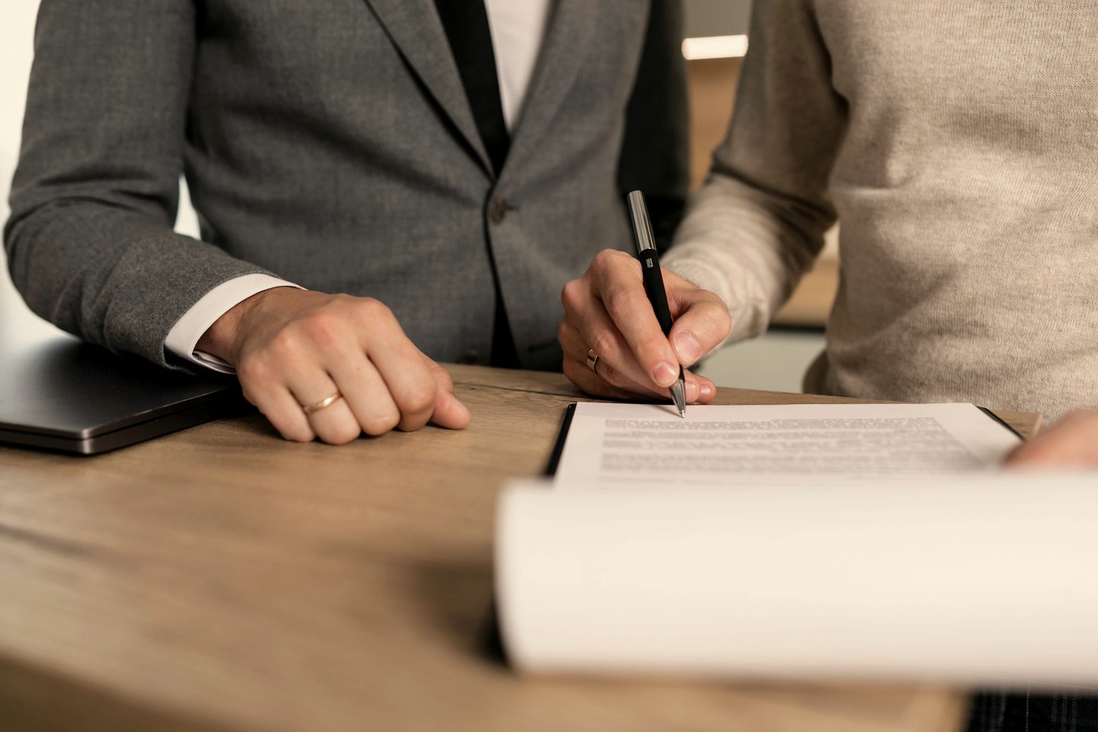 Pessoas assinando documentos em uma mesa de madeira